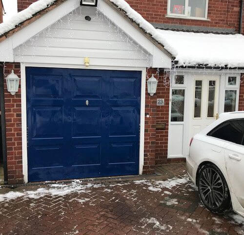 Royal blue garage door fitted for orange brick work house by Chase Garage Doors